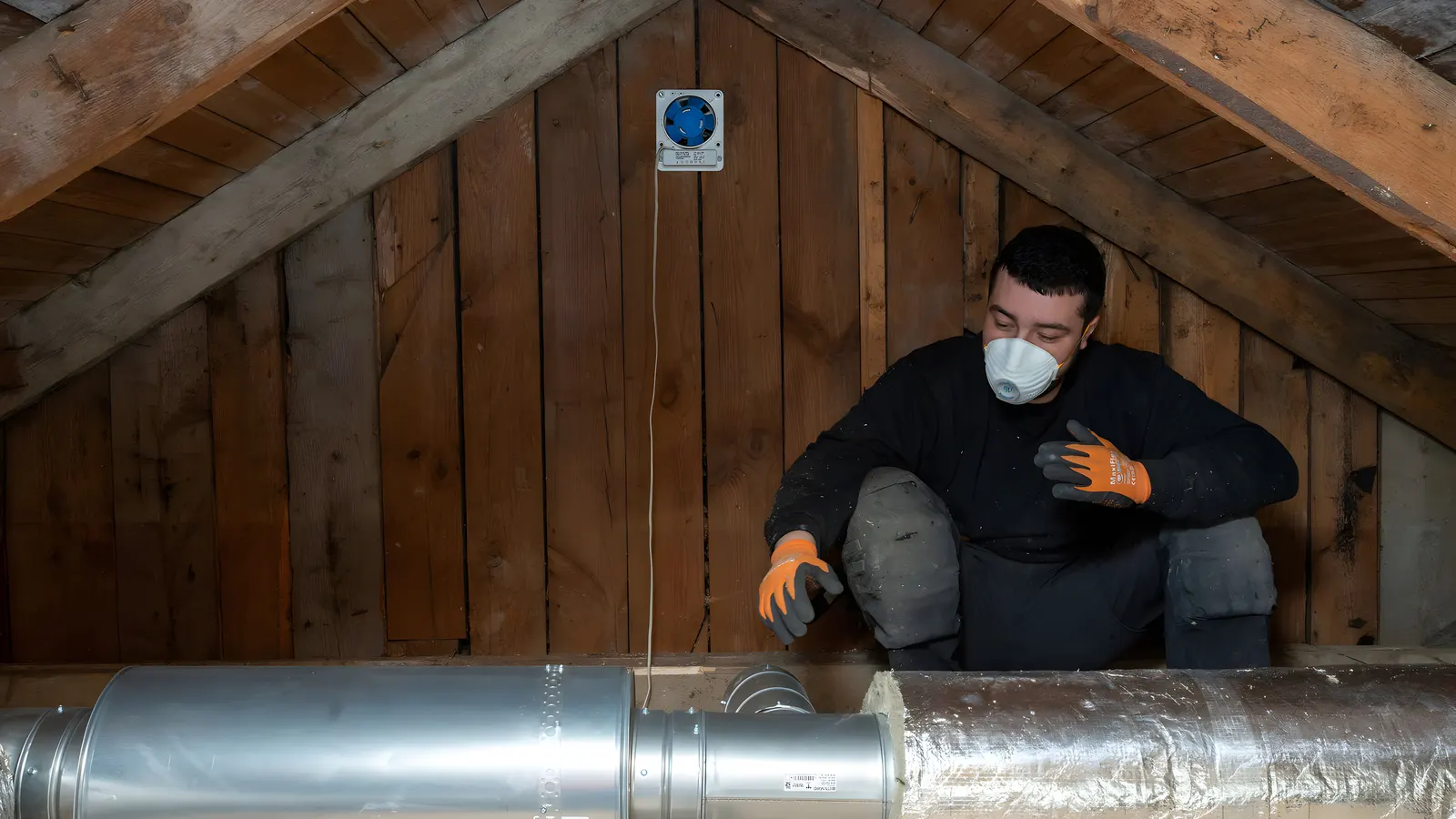 Ventilationstekniker som kontrollerar monterade ventilationskanaler på en vind i Stockholm